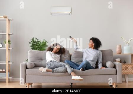Glückliche afroamerikanische Familie, die sich auf dem Sofa unter der Klimaanlage entspannen kann Stockfoto