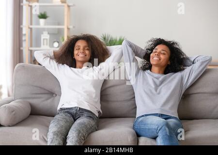 Ruhige afrikanische Familie Mutter und Tochter entspannen sich auf einem bequemen Sofa Stockfoto