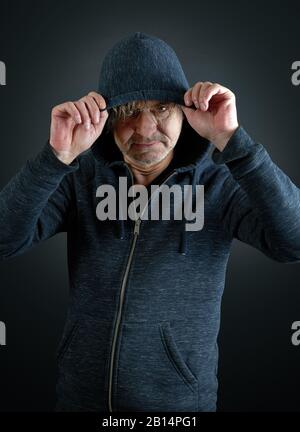 Porträt eines Mannes, der sein Kapuzenhemd auf einem Verlaufshintergrund hält Stockfoto