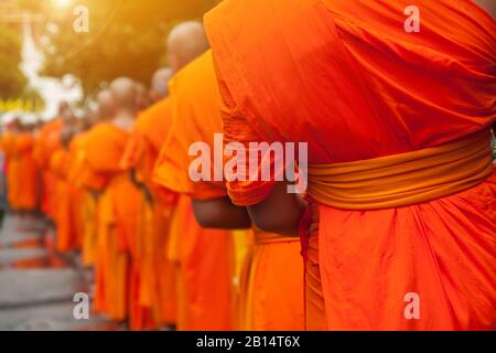 Buddhistische Philanthropie Konzept. Buddhistische Mönche Reihen sich in Reihe, warten auf die buddhistischen Leute, um Almosenschüssel im thailändischen Tempel am Morgen zu geben. Stockfoto