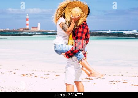 Liebespaar küsst sich mit Liebe - Konzept für Sommerurlaub oder Flitterwochen für Menschen in Beziehung - Hintergrund mit Strand und blauem Meer und Himmel - Stockfoto