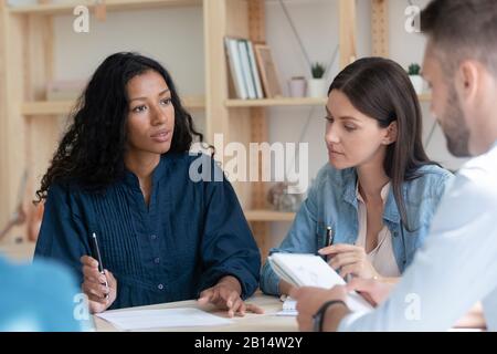 Konzentrierte Kollegen, die über Arbeitsfragen im Büro sprechen. Stockfoto