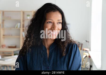 Lächelnde junge afroamerikanische Mitarbeiterin denkt an Karrierechancen. Stockfoto