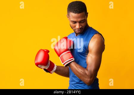 Gutaussehender Afro Sportmann bereit für den Kampf im Orange Studio Stockfoto