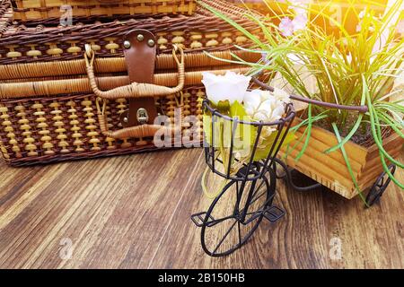 Sommerferienkonzept: Vintage-Koffer auf dem Tisch mit Blumentopf in kleiner Fahrradform. Kopierraum auf Holztisch Stockfoto