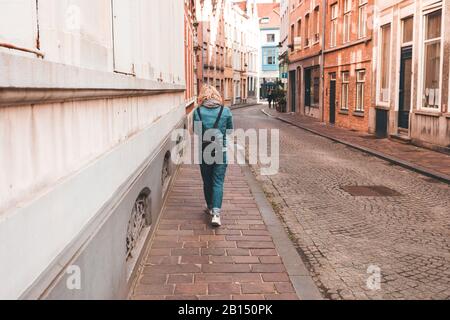 Eine Frau läuft auf einer leeren Straße in Brügges, Belgien. Stockfoto