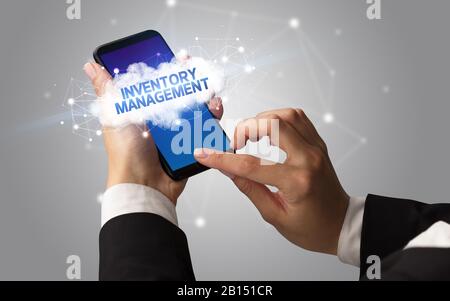 Weibliche Hand berühren Smartphone mit Inventory Management Inschrift, Cloud Business Konzept Stockfoto