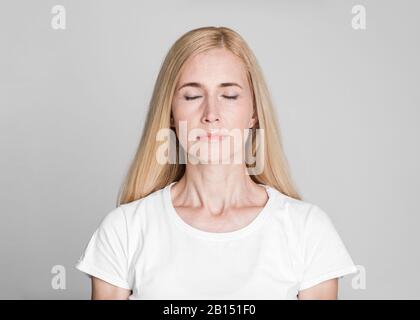 Schöne Frau mittleren Alters, die mit geschlossenen Augen posiert Stockfoto