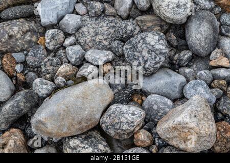Steine aus Granit schließen Texturhintergrund. Glaziale raue natürliche graue Steine auf der Flussseite. Musterressourcen Stockfoto