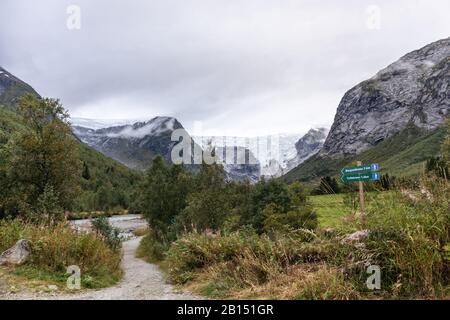 Markierung der Route des Jostedalsbreen-Gletschers. Blick auf die Landschaft der grünen Berge. Wandertour durch die Natur Norwegens am bewölkten Herbsttag Stockfoto