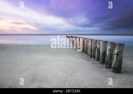 Posts am Nordseestrand bei Sonnenuntergang, Niederlande, Zeeland, Nieuw-Haamstede Stockfoto