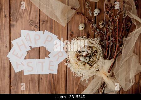 Flache Laienzusammensetzung aus Wachteleiern und Karte mit Text Happy Easter auf Holztisch. Draufsicht. Stockfoto