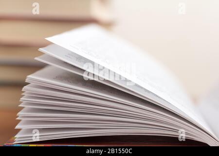 Öffnen Sie das Buch aus der Nähe vor dem Hintergrund der Bücherregale Stockfoto