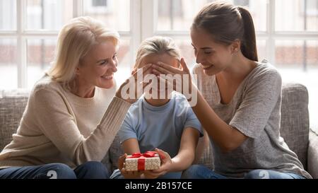 Glückliche Großmutter mittleren Alters und junge Mutter, die die Augen der Mädchen bedeckt. Stockfoto