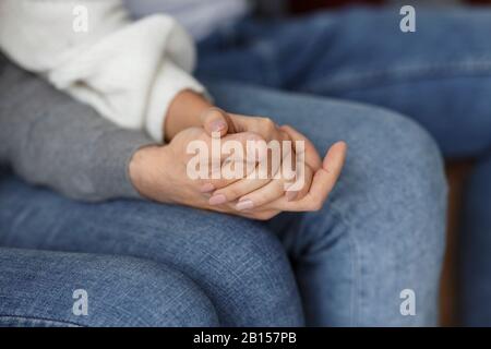 Ehepartner Halten Sich Hände, Die Sich Gegenseitig Stützen Sitzend Im Innenbereich, Zugeschnitten Stockfoto