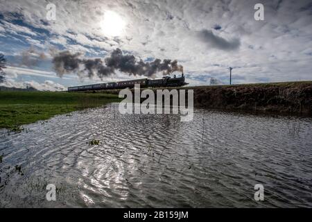 Bury Lancashire, 23. Februar 2020. Eine Dampfmaschine transportiert Passagiere entlang der East Lancashire Railway im Grars Country Park, während sie nach starkem nächtlichen Regen überflutete Felder passieren. Der blaue Himmel begrüßte die Besucher bei einer kurzen Wetterpause am Sonntagmorgen, bevor der nächste Sturm über Nacht im Nordwesten Englands eintreffen soll. Credit: Paul Heyes/Alamy Live News Stockfoto