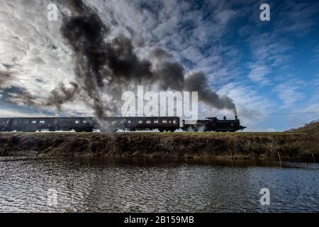 Bury Lancashire, 23. Februar 2020. Eine Dampfmaschine transportiert Passagiere entlang der East Lancashire Railway im Grars Country Park, während sie nach starkem nächtlichen Regen überflutete Felder passieren. Der blaue Himmel begrüßte die Besucher bei einer kurzen Wetterpause am Sonntagmorgen, bevor der nächste Sturm über Nacht im Nordwesten Englands eintreffen soll. Credit: Paul Heyes/Alamy Live News Stockfoto