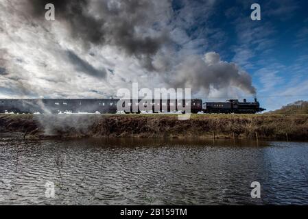 Bury Lancashire, 23. Februar 2020. Eine Dampfmaschine transportiert Passagiere entlang der East Lancashire Railway im Grars Country Park, während sie nach starkem nächtlichen Regen überflutete Felder passieren. Der blaue Himmel begrüßte die Besucher bei einer kurzen Wetterpause am Sonntagmorgen, bevor der nächste Sturm über Nacht im Nordwesten Englands eintreffen soll. Credit: Paul Heyes/Alamy Live News Stockfoto