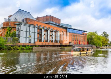 Ein buntes Vergnügungsboot führt Touristen am Royal Shakespeare Company Theatre am Fluss Avon, Stratford upon Avon, Warwickshire, England, Großbritannien vorbei Stockfoto