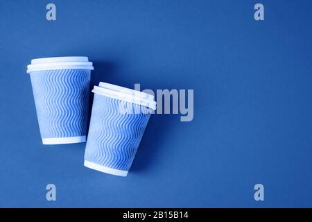 Zwei Pappkaffeetassen auf blauem Hintergrund. Stockfoto