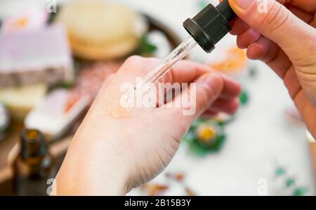 Natürliche Hautpflege, Frau Hand mit natürlichem Öl für Hautpflege, mit Ölflasche, sauberer Schönheit natürliche Hautpflege Blumengesicht und Körperöl, vegane Haut Stockfoto