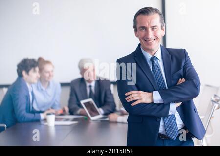 Porträt eines reifen Geschäftsmannes vor seinem Team im Büro-Kopierraum für Text Stockfoto