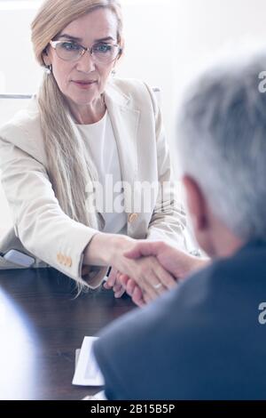 Geschäftsleute schütteln die Hände am Treffpunkt und konzentrieren sich auf die reife Frau Stockfoto