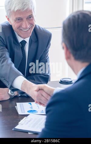 Geschäftsleute schütteln die Hände am Besprechungstisch glücklich lächelnd erfolgreiches Verhandlungskonzept Stockfoto