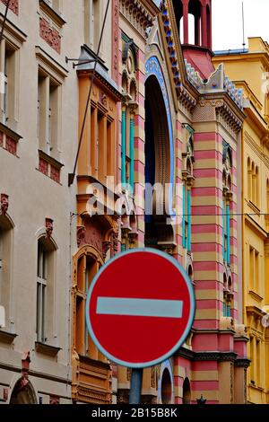 Ein rotes Stoppschild, im Gegensatz zu den hellen Farben und maurischen Formen der Jubilee Synagogengemeinde - Jerusalem Synagogengemeinde; jüdische Kirche Nové Město, Prag Stockfoto