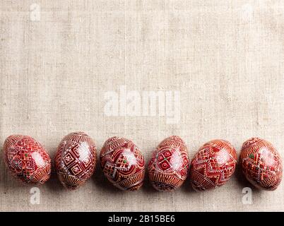 Traditioneller ukrainischer Pysanka auf Leinen-Stoff-Hintergrund in Reihe gestellt. Dekorierte Ostereier, traditionell für osteuropäische Kultur. Flaches Lay, oben V Stockfoto