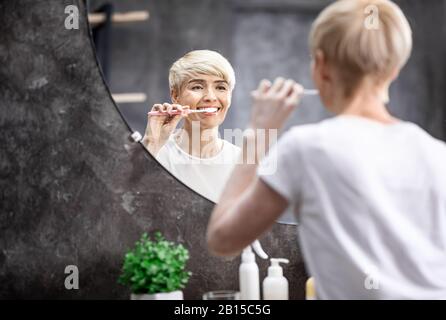 Frau Putzte Morgens Weiße Zähne, Die Im Bad Stehen Stockfoto