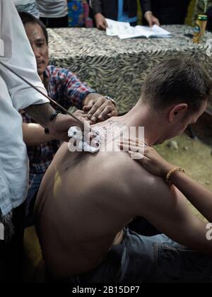 Tätowierkünstler, der einem Mann ein Hintertattoo zuwendet. Thailand, Südostasien Stockfoto