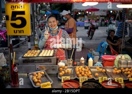 Frau, die japanische Takoyaki-Knödel auf einem thailändischen Straßennahrungsmarkt kocht und verkauft. Thailand S. E. Asien. Stockfoto