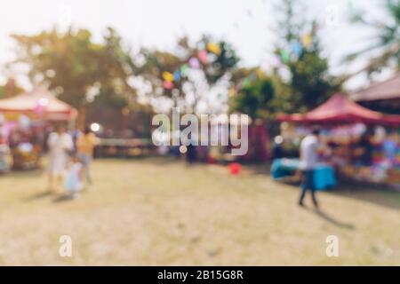 Abstrakte Verwacklungen von Menschen und Sonnenlicht auf dem Festival im Stadtparkgarten mit Bokeh-Hintergrund. Stockfoto