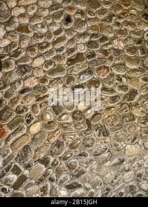 Boden aus Kieselsteinen des Flusses. Alte, verwitterte und zupfte Kopfsteinpflaster, aus runden Flusssteinen unterschiedlicher Größe, verfugt mit Mörtel. Nahaufnahme. Stockfoto