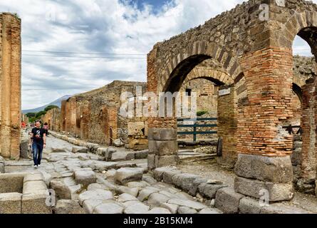 Pompeji, ITALIEN - 13. MAI 2014: Touristenspaziergänge in der Straße unter den Ruinen. Pompeji ist eine alte römische Stadt, die durch den Ausbruch des Vesuviu gestorben ist Stockfoto