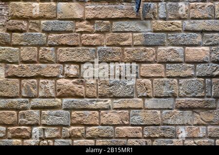 Mauer aus Backstein oder Stein eines alten Hauses an der Straße in Florenz, Italien. Hintergrund. Stockfoto