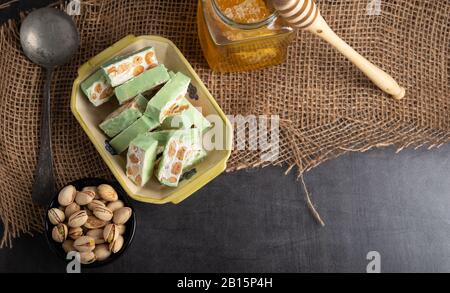 Bio Nougat mit Honig, Pistazie, Haselnuss und Mandel Mutter Muttern auf einem rustikalen dunklen Hintergrund. Stockfoto