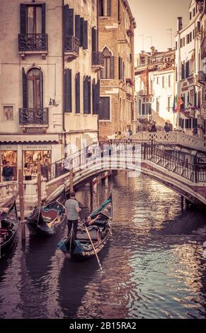 Venedig, Italien - 21. Mai 2017: Gondel mit Touristen schwimmt entlang der alten schmalen Straße mit kleinen Brücken. Gondel ist das attraktivste Touristentra Stockfoto