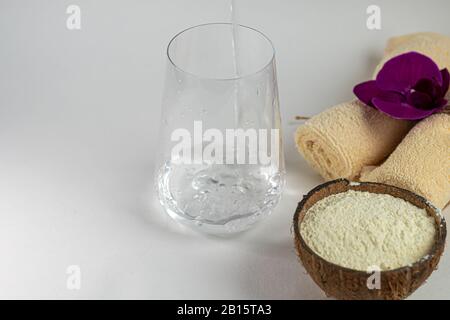 Kollagenpulver in halber Kokosnuss mit einem Löffel zur Messung der Menge. Zusätzliche Proteinaufnahme. Stockfoto