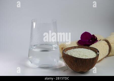 Kollagenpulver in halber Kokosnuss mit einem Löffel zur Messung der Menge. Zusätzliche Proteinaufnahme. Stockfoto