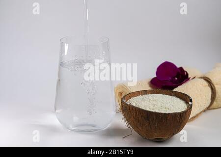 Kollagenpulver in halber Kokosnuss mit einem Löffel zur Messung der Menge. Zusätzliche Proteinaufnahme. Stockfoto