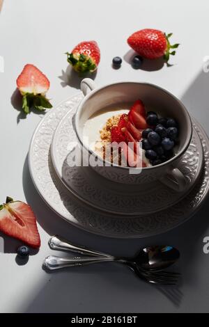 Gesundes Frühstück: Joghurt mit frischen Erdbeeren und Blaubeeren, Müsli und Cornflakes, Glas frischen Orangensaft. Stockfoto