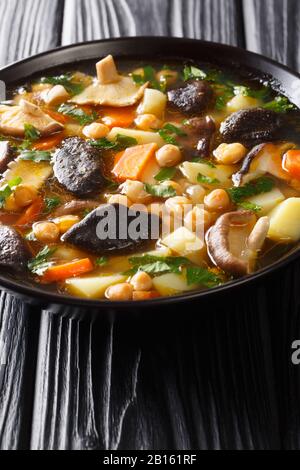 Pilzsuppe mit Kichererbsen und Gemüse in einer Schüssel auf dem Tisch. Vertikal Stockfoto
