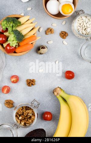 Lebensmittel: Tomateneier Walnüsse Bohnen Mais Avocado Broccoli Karotten Bananen auf blauem Grund, natürliche Lebensmittel Draufsicht Flat Lay Stockfoto