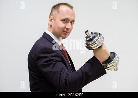 Kaufmann im schwarzen Anzug eine silberne Hantel in die Rechte Hand hält Stockfoto