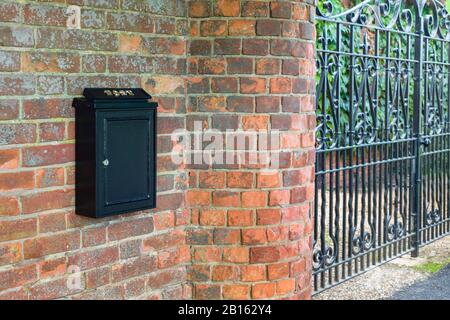 Briefkasten und schmiedeeiserne Tore am Eingang zu einem englischen Haus, Großbritannien Stockfoto