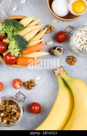 Lebensmittel: Tomateneier Walnüsse Bohnen Mais Avocado Broccoli Karotten Bananen auf blauem Grund, natürliche Lebensmittel Draufsicht Flat Lay Stockfoto