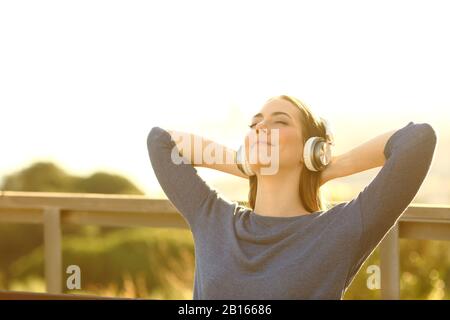 Entspannte junge Frau, die Musik hört und im Freien in der Natur meditiert Stockfoto