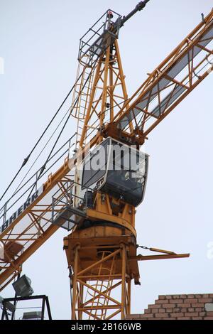 Turmkran arbeitet an einer Baustelle gegen den Himmel. Kran-Führerhaus nah. Stockfoto